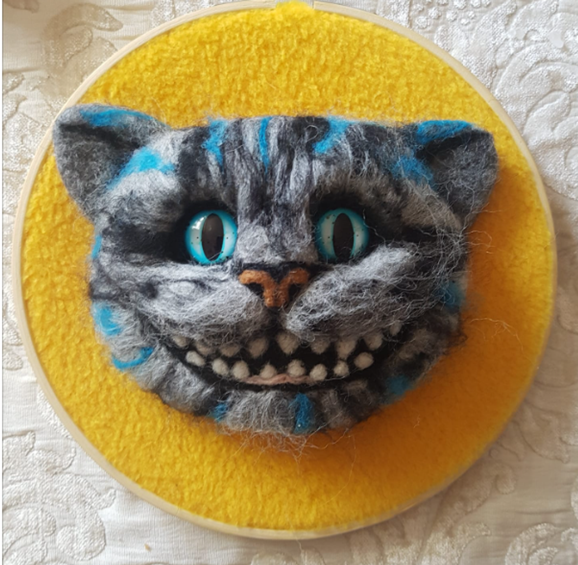 żółty filcowy kwiat na tle drewna i jesiennych liści